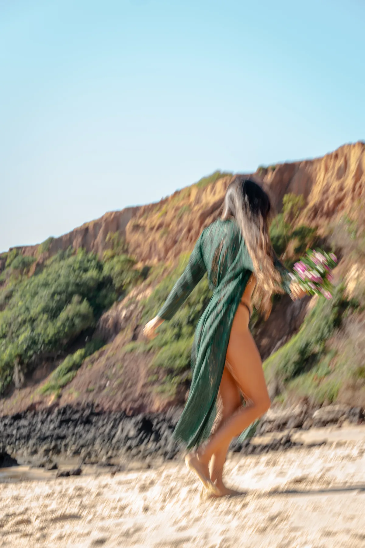 Movimiento desenfocado de una mujer corriendo con flores en la playa