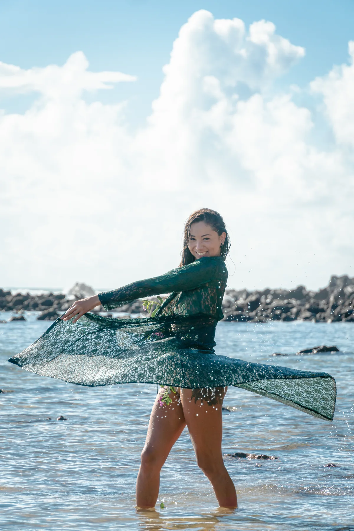 Mujer girando una túnica verde dentro del mar