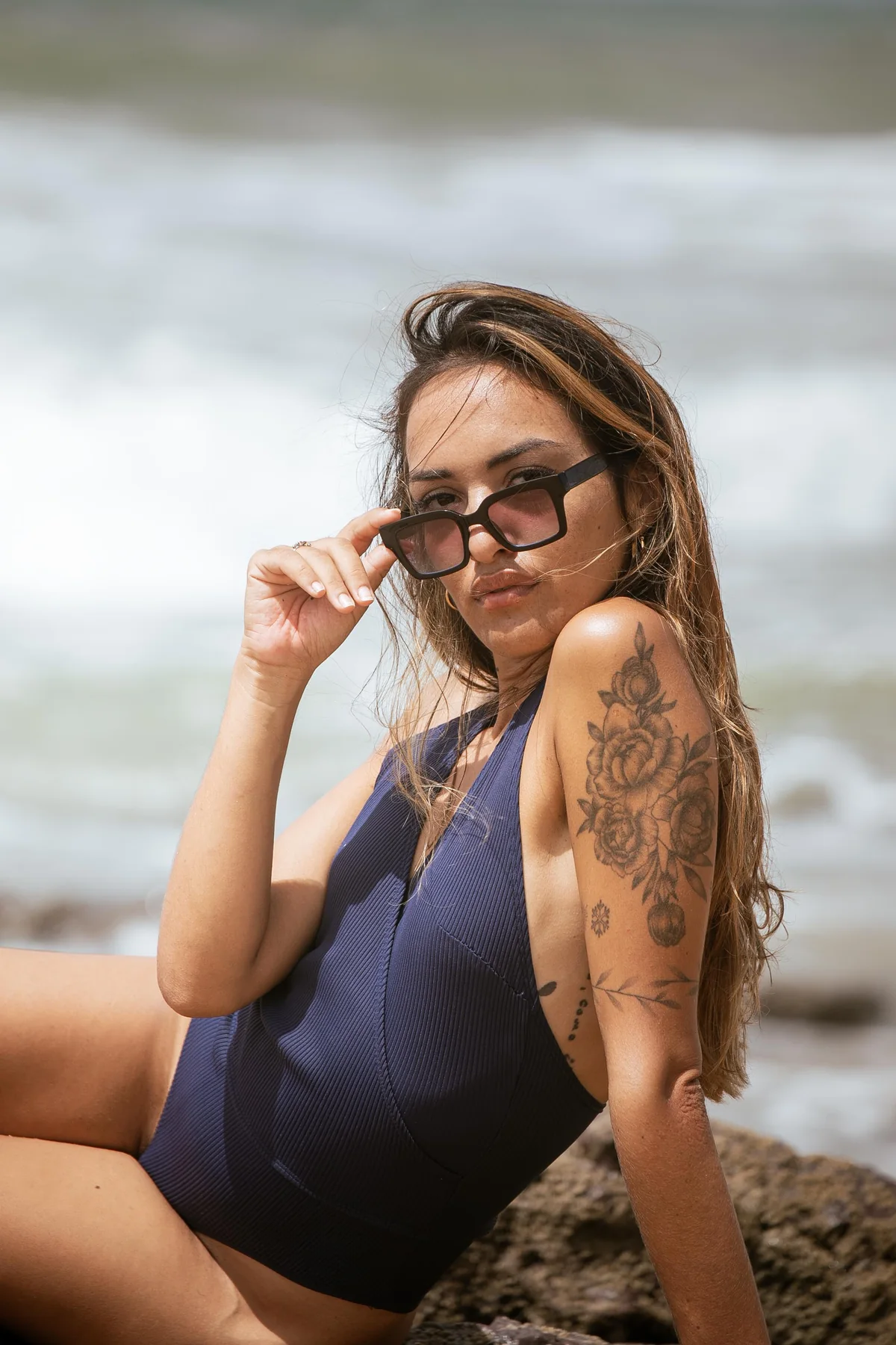 Priscila mirando a cámara con gafas frente al mar