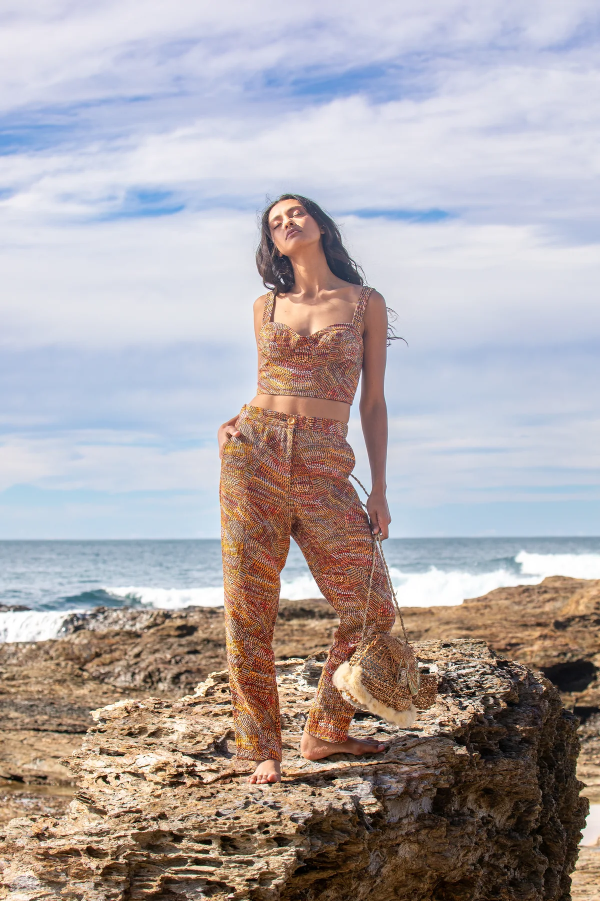 Retrato de pie sobre rocas con conjunto estampado frente al mar