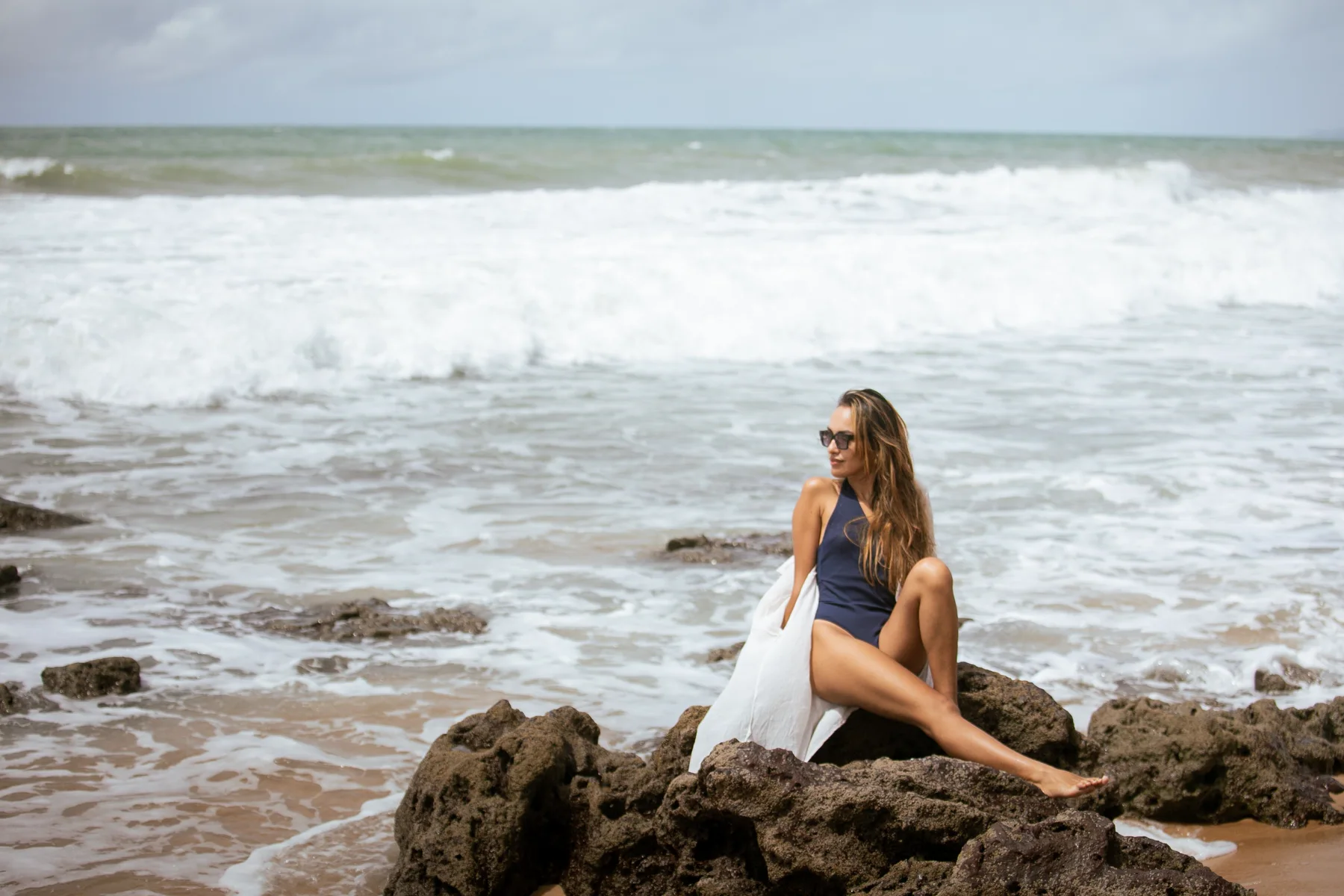 Retrato sentada sobre rocas frente al mar y las olas