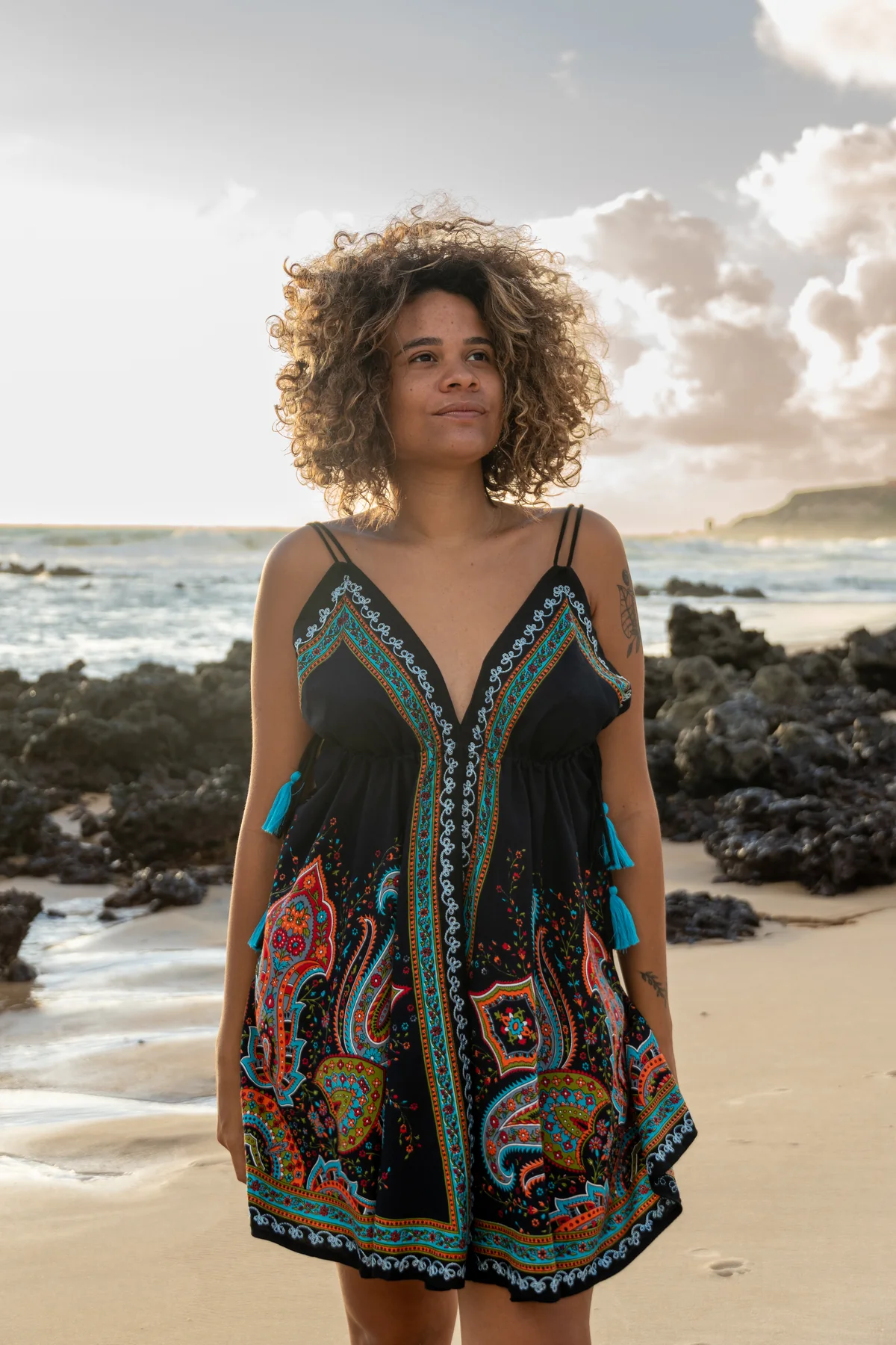 Retrato frontal con vestido estampado en una playa rocosa