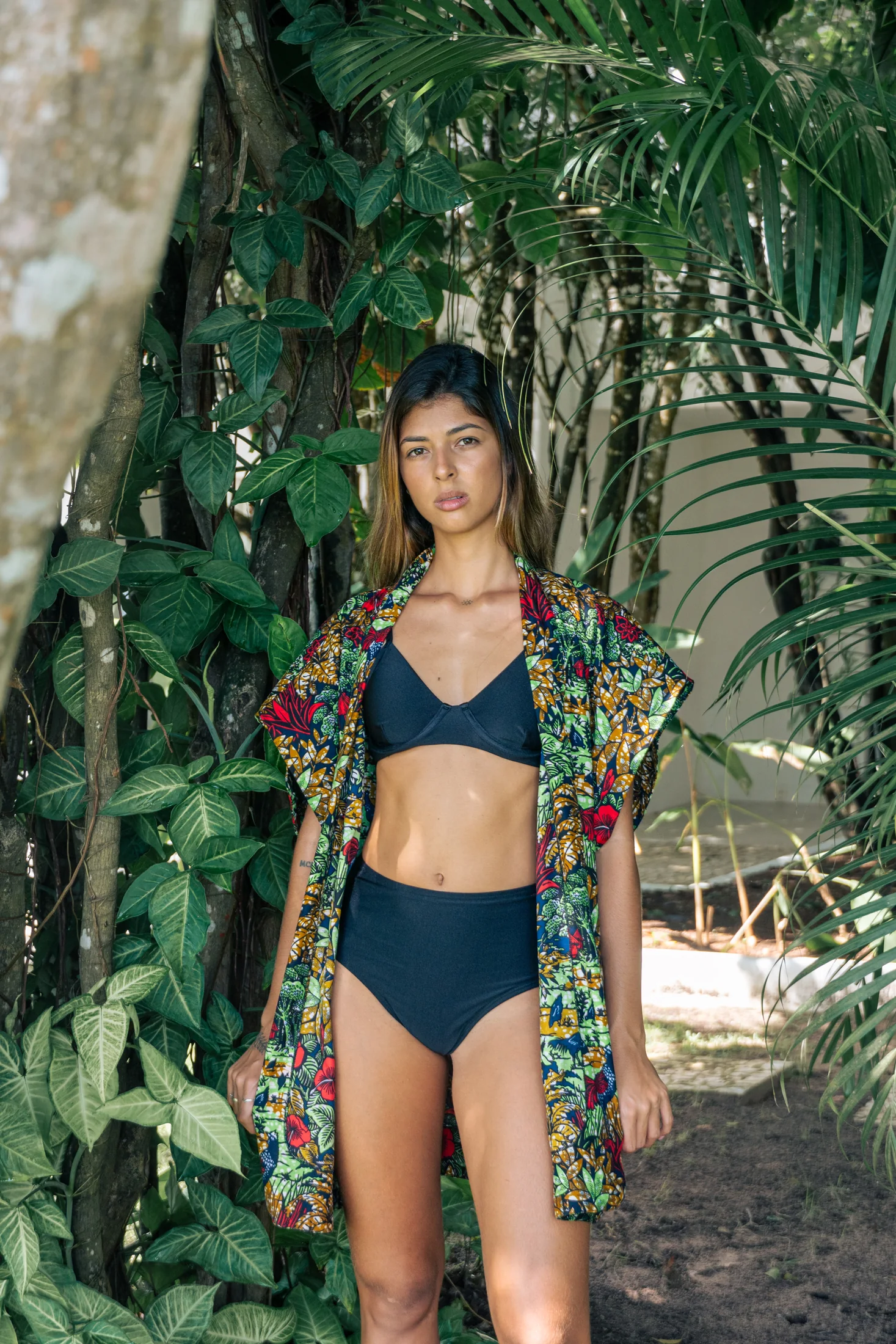 Retrato entre hojas tropicales con traje de baño negro y kimono estampado