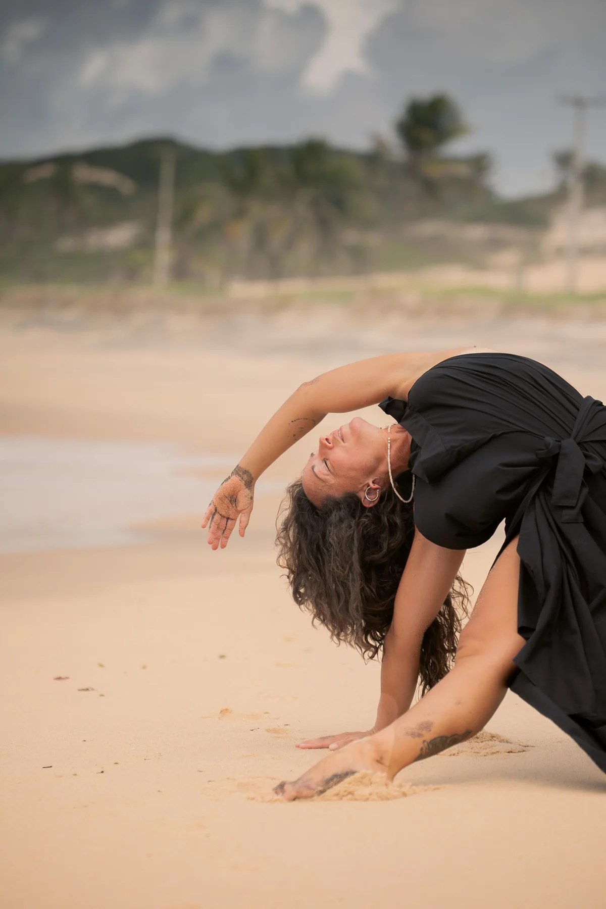 Mujer doblada hacia adelante durante una secuencia de movimiento en la playa