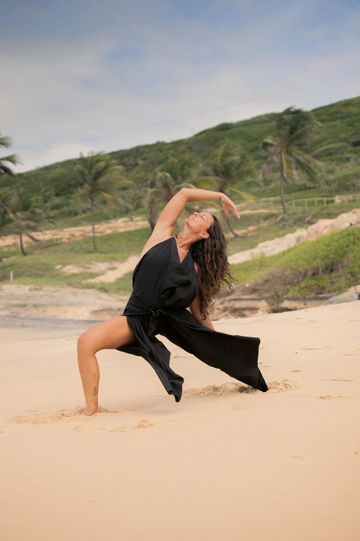 Postura de movimiento en la playa con vestido negro
